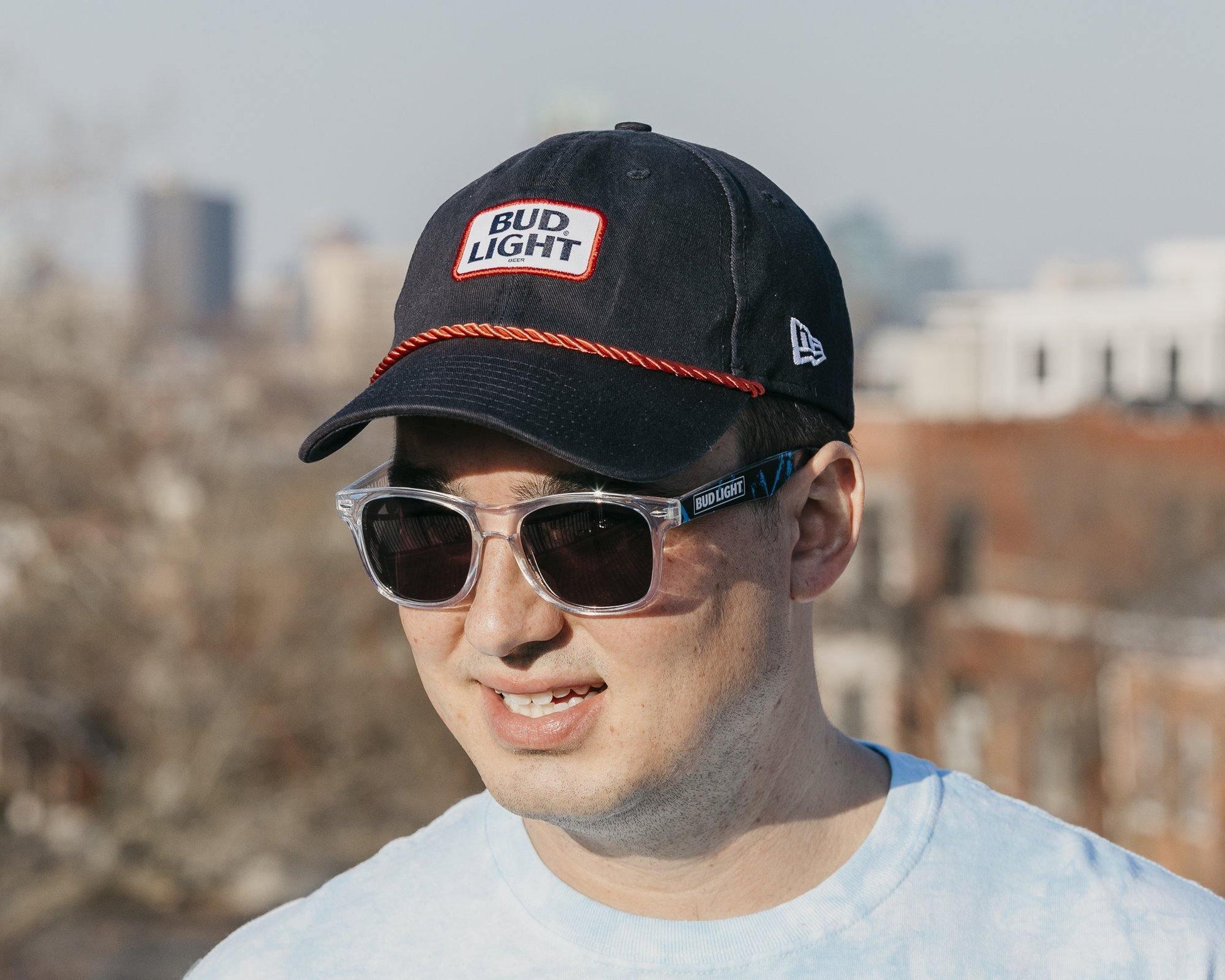 man wearing navy new era adjustable bud light hat with a red rope across the brim of the hat
