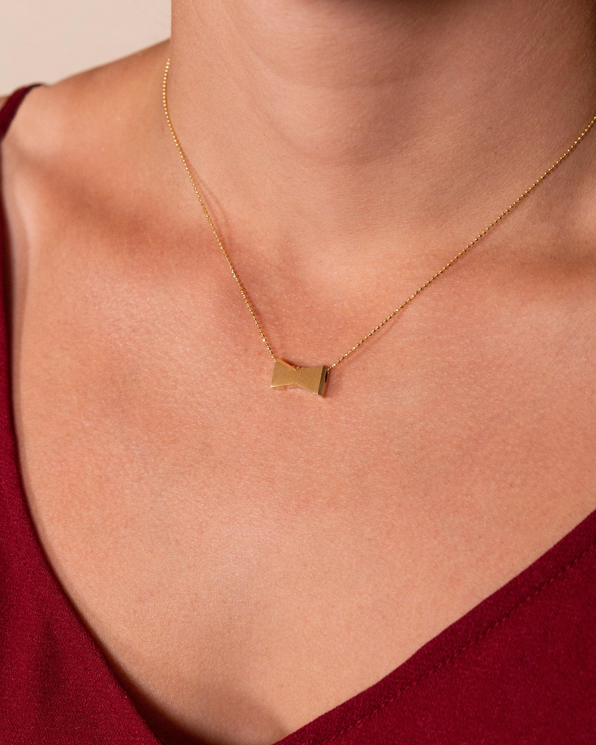 woman wearing necklace 14 carat gold Budweiser bowtie necklace