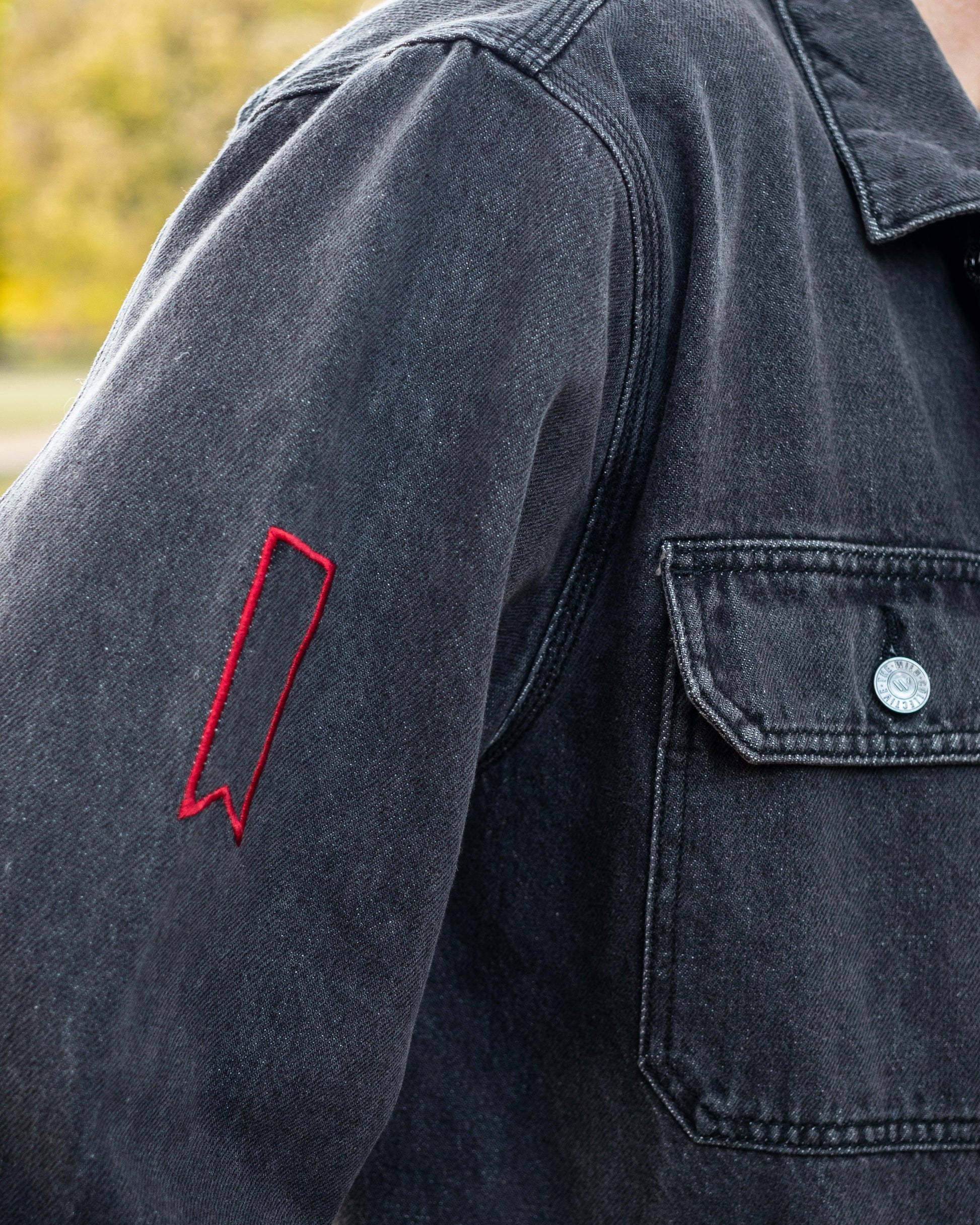 model wearing jean jacket with detail of open red ribbon 