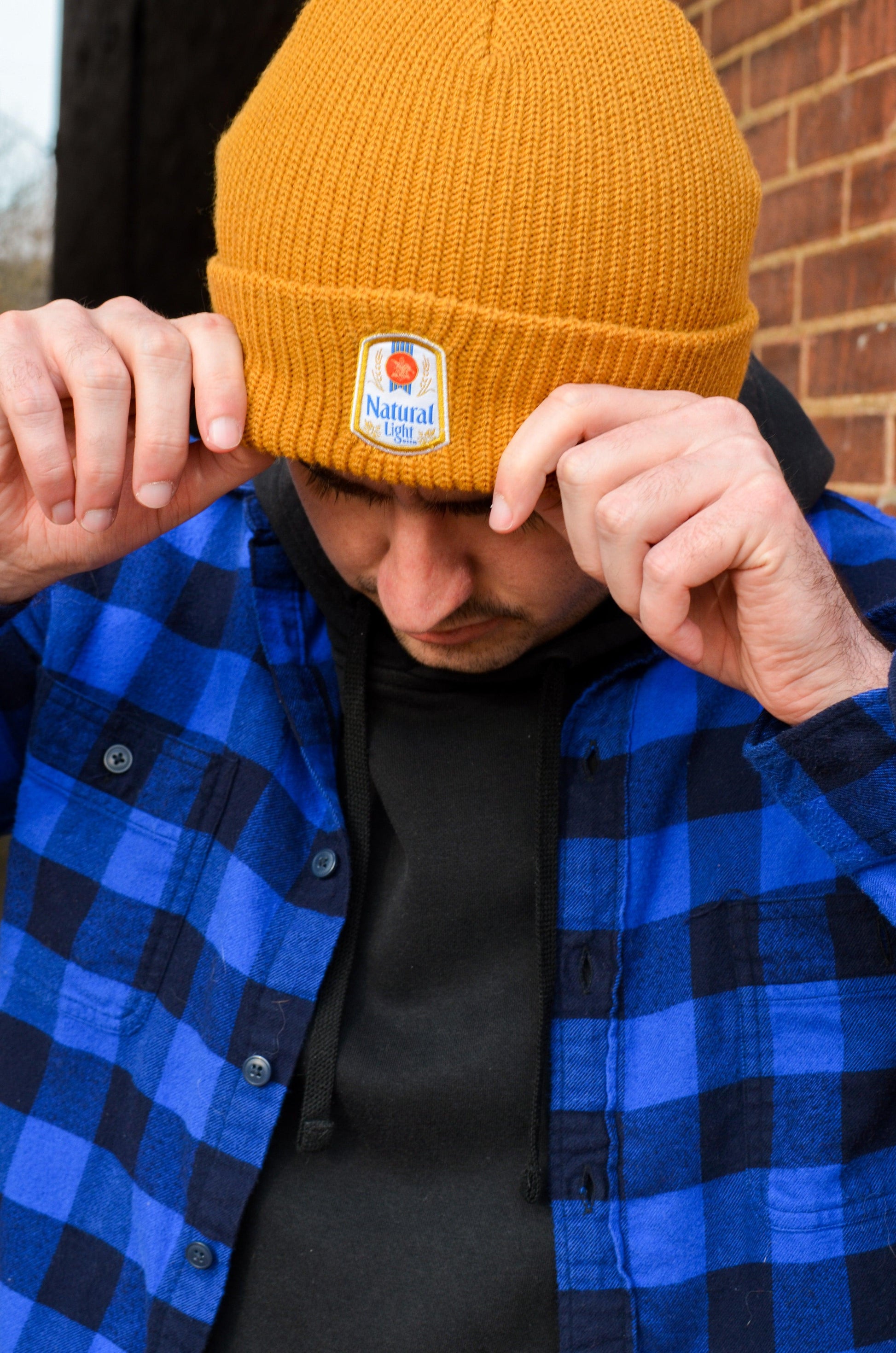 man wearing orange brown natural light beanie with vintage logo patch on front
