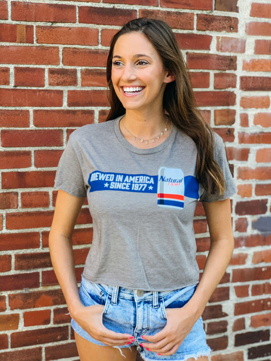 woman wearing grey natural light womens american brewed crop t shirt that says brewed in america since 1977